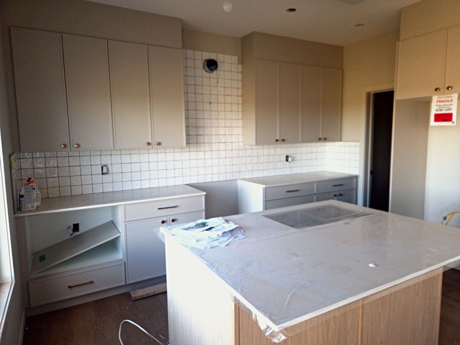 Kitchen with white shaker cabinets to the ceiling, square tile backsplash, quartz counters and a white-oak island