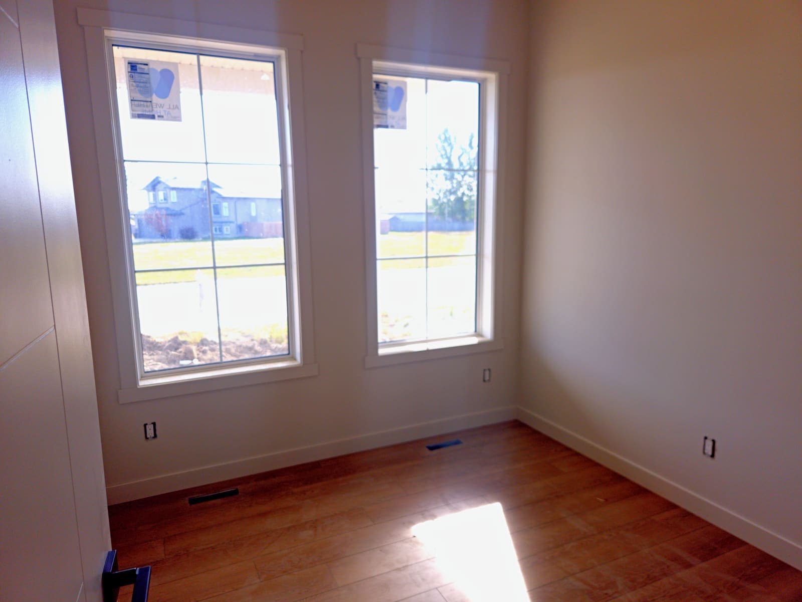 Main-floor room with oak luxury vinyl plank flooring and two grille windows facing the street