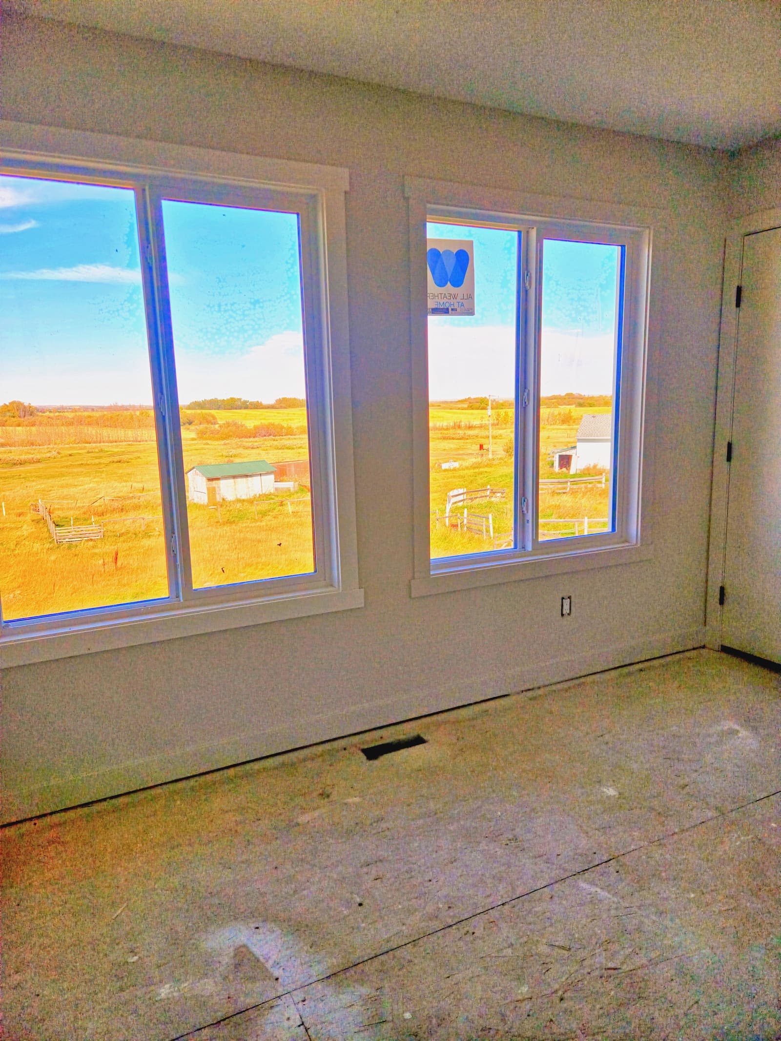 Upstairs bedroom windows looking out over open prairie beyond the subdivision